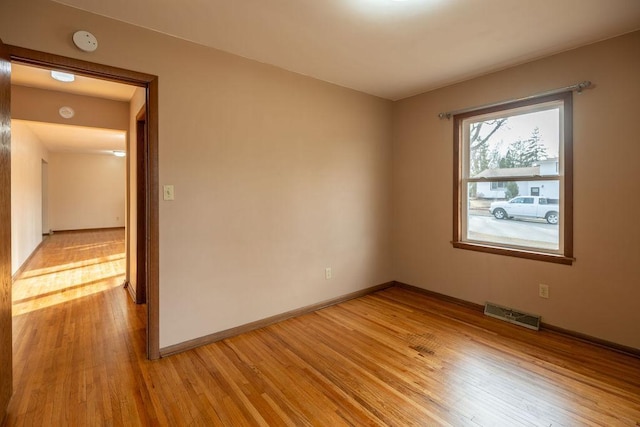 empty room featuring baseboards, visible vents, and light wood-type flooring