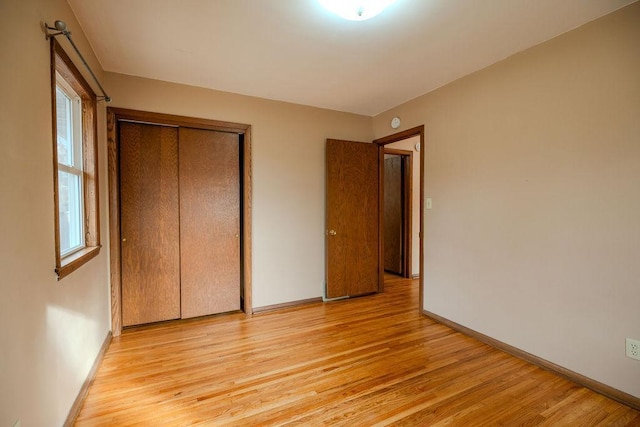 unfurnished bedroom with a closet, baseboards, and light wood-style floors