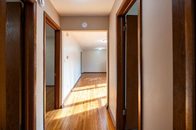 corridor featuring light wood-style flooring and baseboards