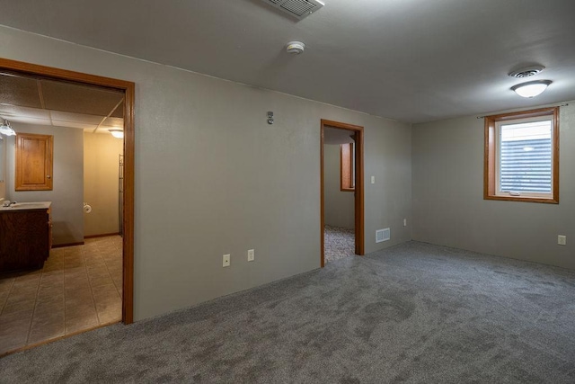 spare room featuring light tile patterned flooring, visible vents, and light carpet