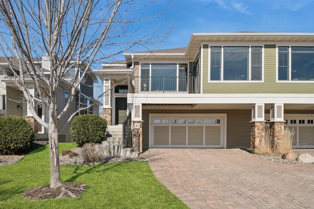 view of front facade featuring a front yard, a balcony, decorative driveway, and a garage