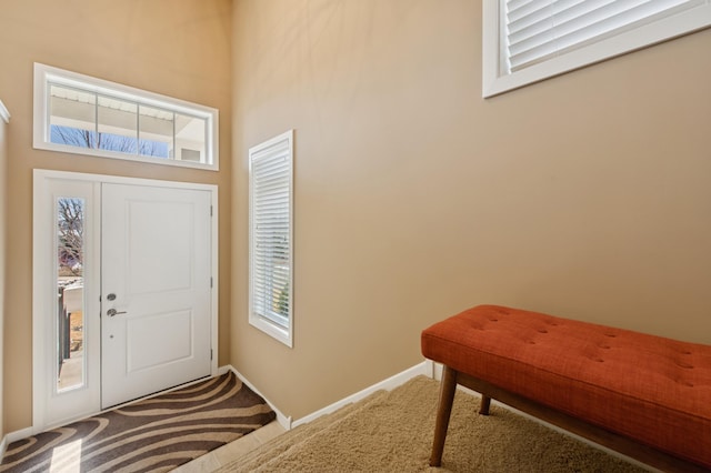 foyer entrance featuring baseboards and carpet floors