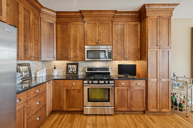 kitchen with light wood-type flooring, stainless steel appliances, and brown cabinets