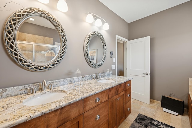 bathroom featuring a sink, baseboards, double vanity, and a tile shower