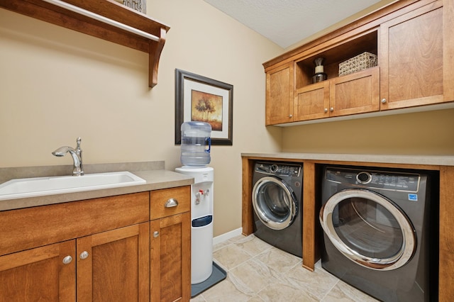 laundry area featuring cabinet space, washing machine and dryer, baseboards, and a sink