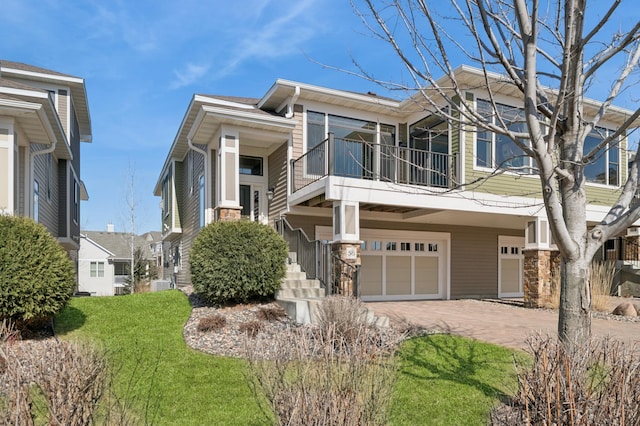 view of front facade with central air condition unit, a balcony, decorative driveway, and a garage