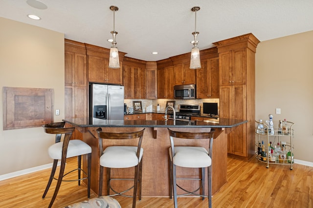 kitchen with dark countertops, light wood-style flooring, backsplash, and stainless steel appliances