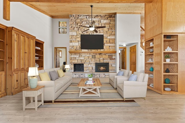 living area featuring wood finished floors, a stone fireplace, ceiling fan, and wooden ceiling