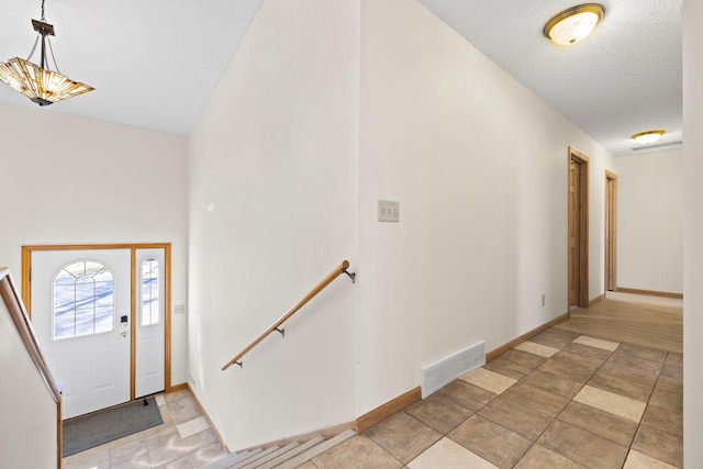 foyer with visible vents, a textured ceiling, and baseboards