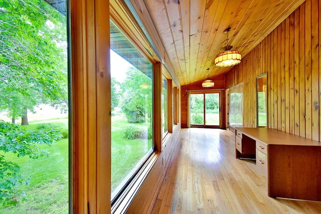 corridor with lofted ceiling, wooden walls, light wood-style flooring, and wooden ceiling