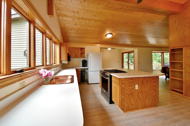 kitchen featuring open shelves, lofted ceiling, freestanding refrigerator, a sink, and stainless steel gas range oven