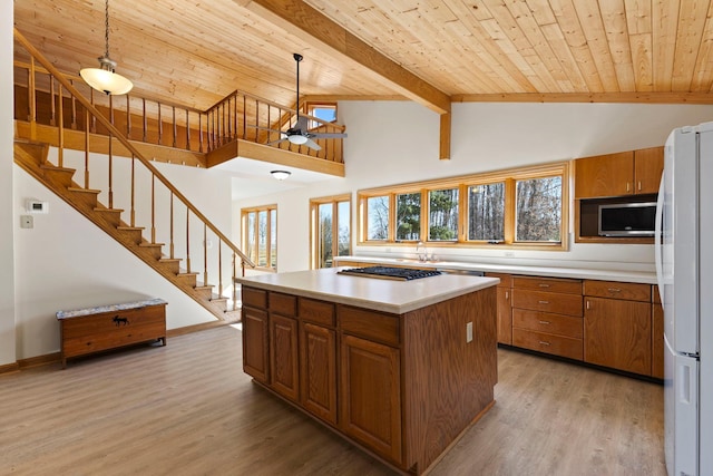 kitchen with stainless steel microwave, brown cabinets, and freestanding refrigerator