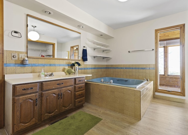 full bath featuring vanity, a garden tub, wood finished floors, and visible vents