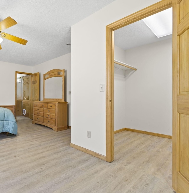 bedroom with ceiling fan, a textured ceiling, baseboards, and wood finished floors