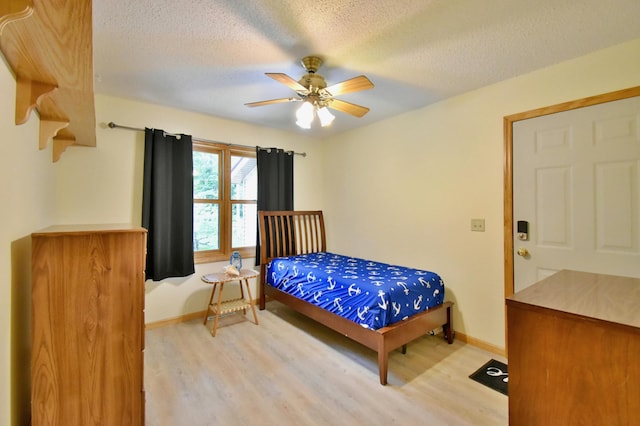 bedroom featuring ceiling fan, light wood-style floors, baseboards, and a textured ceiling