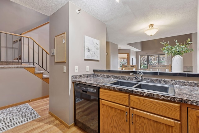 kitchen featuring dark countertops, dishwasher, a textured ceiling, and a sink