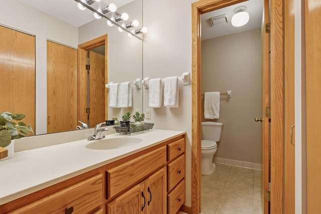 bathroom featuring tile patterned floors, baseboards, toilet, and vanity