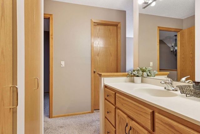 bathroom featuring baseboards, a textured ceiling, and vanity