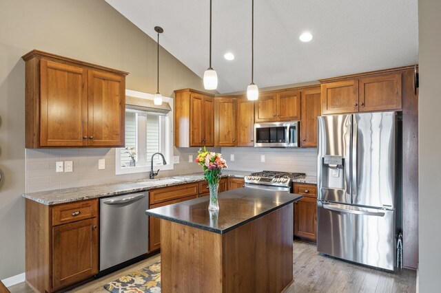 kitchen with vaulted ceiling, stainless steel appliances, and brown cabinets