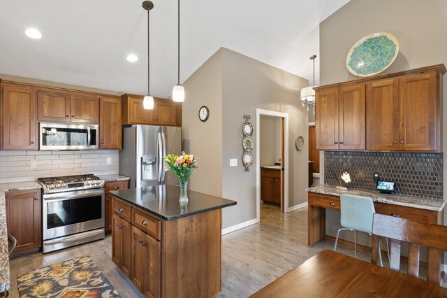 kitchen with light wood-type flooring, brown cabinetry, stainless steel appliances, decorative light fixtures, and decorative backsplash