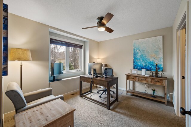 office featuring baseboards, a textured ceiling, carpet, and a ceiling fan