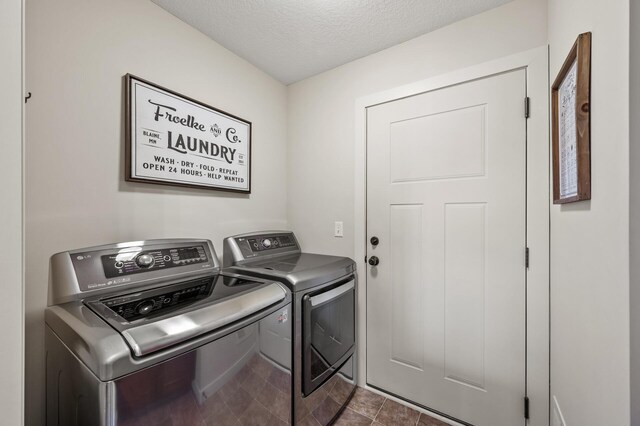 clothes washing area with independent washer and dryer, tile patterned floors, laundry area, and a textured ceiling