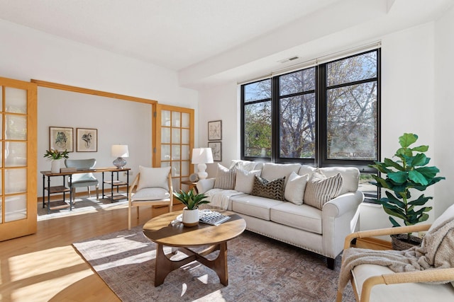 living area with visible vents, wood finished floors, and french doors