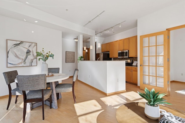 dining area with baseboards, track lighting, and light wood-style floors