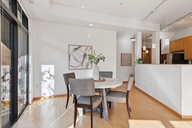 dining room with baseboards, rail lighting, and light wood-style flooring