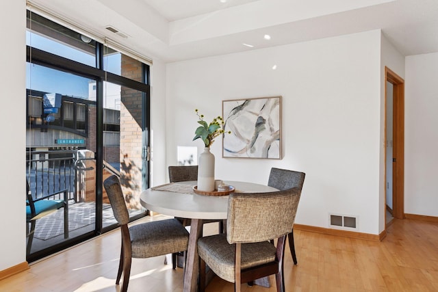 dining area featuring baseboards, expansive windows, wood finished floors, and visible vents