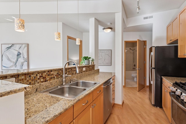 kitchen featuring visible vents, a sink, light wood-style flooring, appliances with stainless steel finishes, and hanging light fixtures