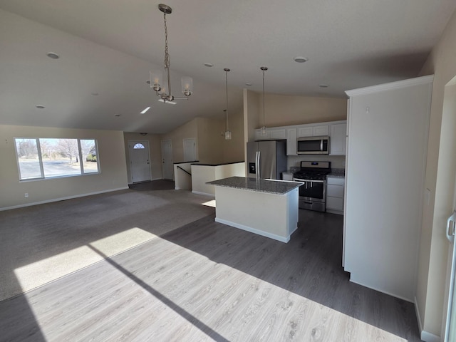 kitchen featuring a kitchen island, open floor plan, lofted ceiling, appliances with stainless steel finishes, and white cabinetry