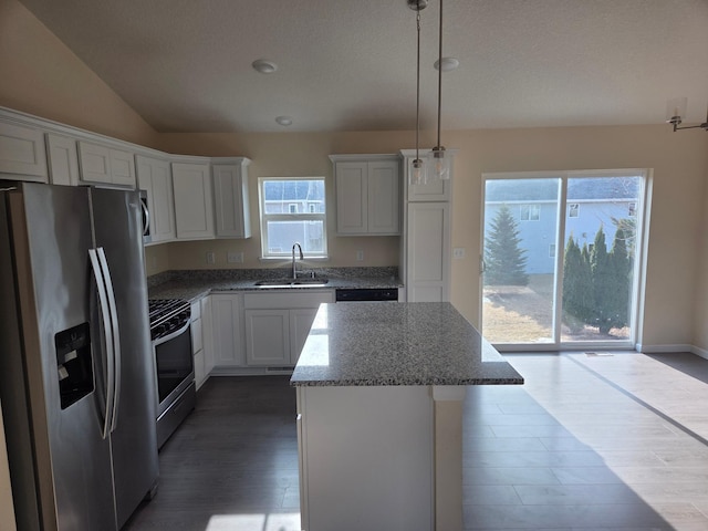 kitchen featuring a kitchen island, dark wood finished floors, a sink, gas range oven, and stainless steel refrigerator with ice dispenser