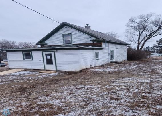 snow covered house featuring a chimney