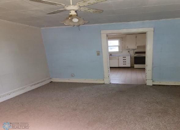 unfurnished living room with baseboards, a ceiling fan, and carpet floors