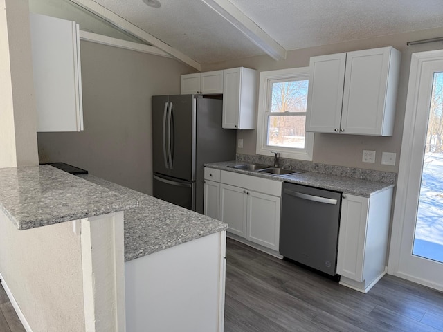 kitchen featuring a peninsula, a sink, stainless steel appliances, dark wood-type flooring, and white cabinetry