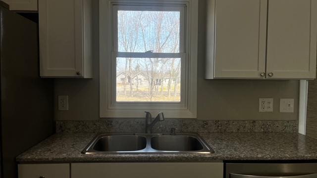 kitchen featuring a sink, stainless steel dishwasher, and white cabinets