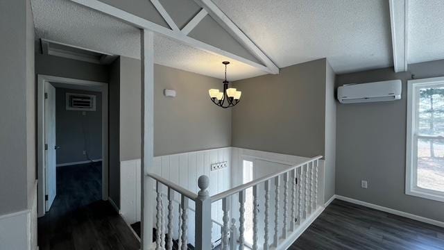 corridor featuring a wall mounted air conditioner, an upstairs landing, an inviting chandelier, wood finished floors, and a textured ceiling