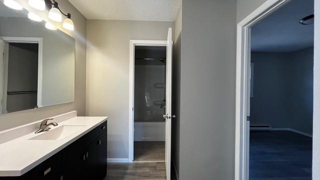 full bathroom featuring baseboards, a textured ceiling, wood finished floors, and vanity