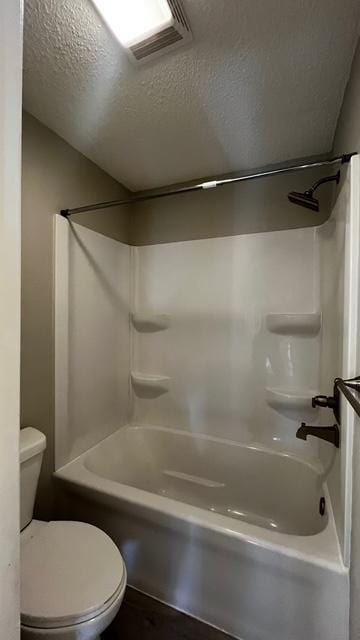 bathroom featuring tub / shower combination, visible vents, a textured ceiling, and toilet