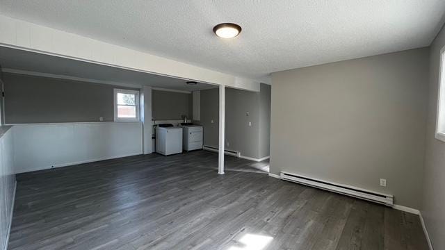 interior space featuring a baseboard heating unit, wood finished floors, washer and dryer, a textured ceiling, and a baseboard radiator