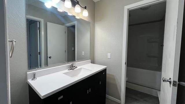 bathroom with toilet, vanity, baseboards, and a textured wall