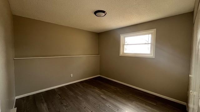 unfurnished room with baseboards, a textured ceiling, and dark wood finished floors