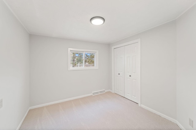 unfurnished bedroom with visible vents, baseboards, a closet, and light carpet