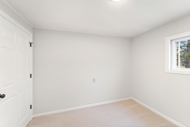 spare room featuring light colored carpet and baseboards