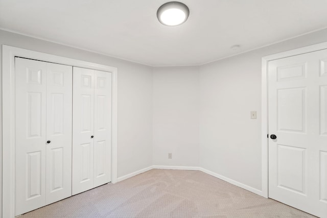 unfurnished bedroom with a closet, baseboards, and light colored carpet