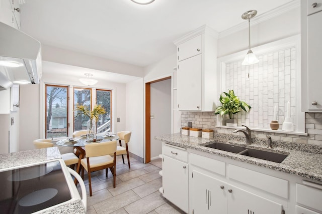 kitchen featuring a sink, decorative backsplash, decorative light fixtures, and white cabinetry