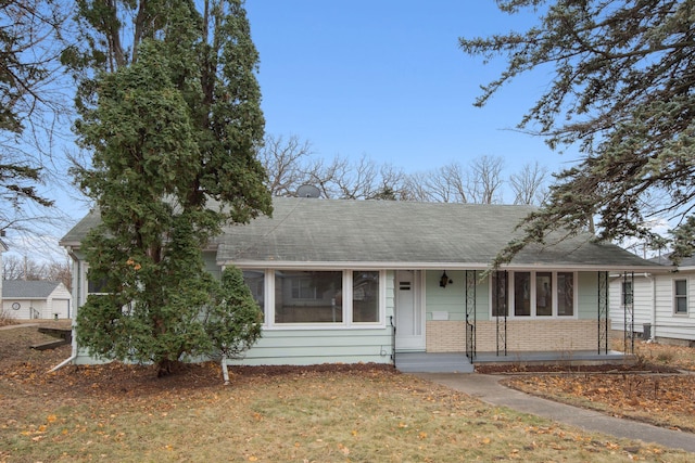 view of front of home with brick siding, a shingled roof, and a front yard