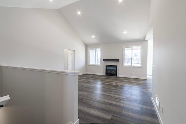 unfurnished living room featuring high vaulted ceiling, dark wood-style floors, a glass covered fireplace, recessed lighting, and baseboards