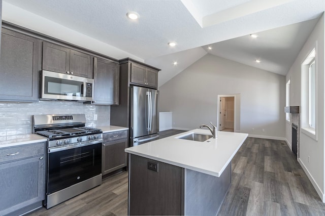 kitchen with dark wood-style flooring, a sink, vaulted ceiling, light countertops, and appliances with stainless steel finishes